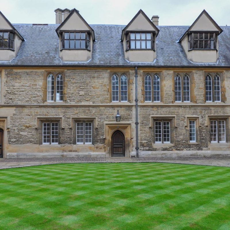 View of english lawn and building facade from Trinity College Durham Quad, Oxford, United Kingdom. Overcast Sky.
